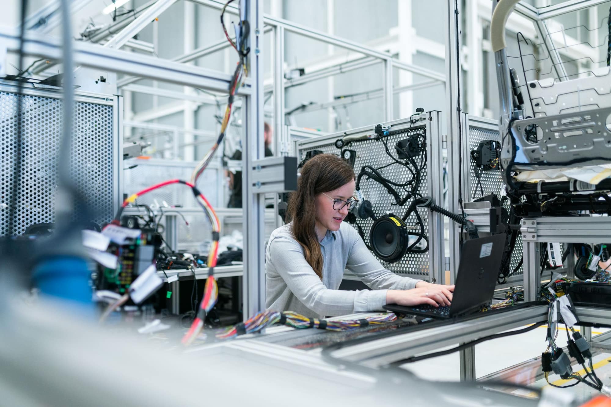 Engineer working on a laptop between test rigs on a production line