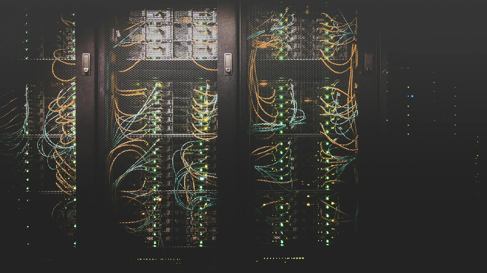 Dark server cabinets laced with patch cables and status lights